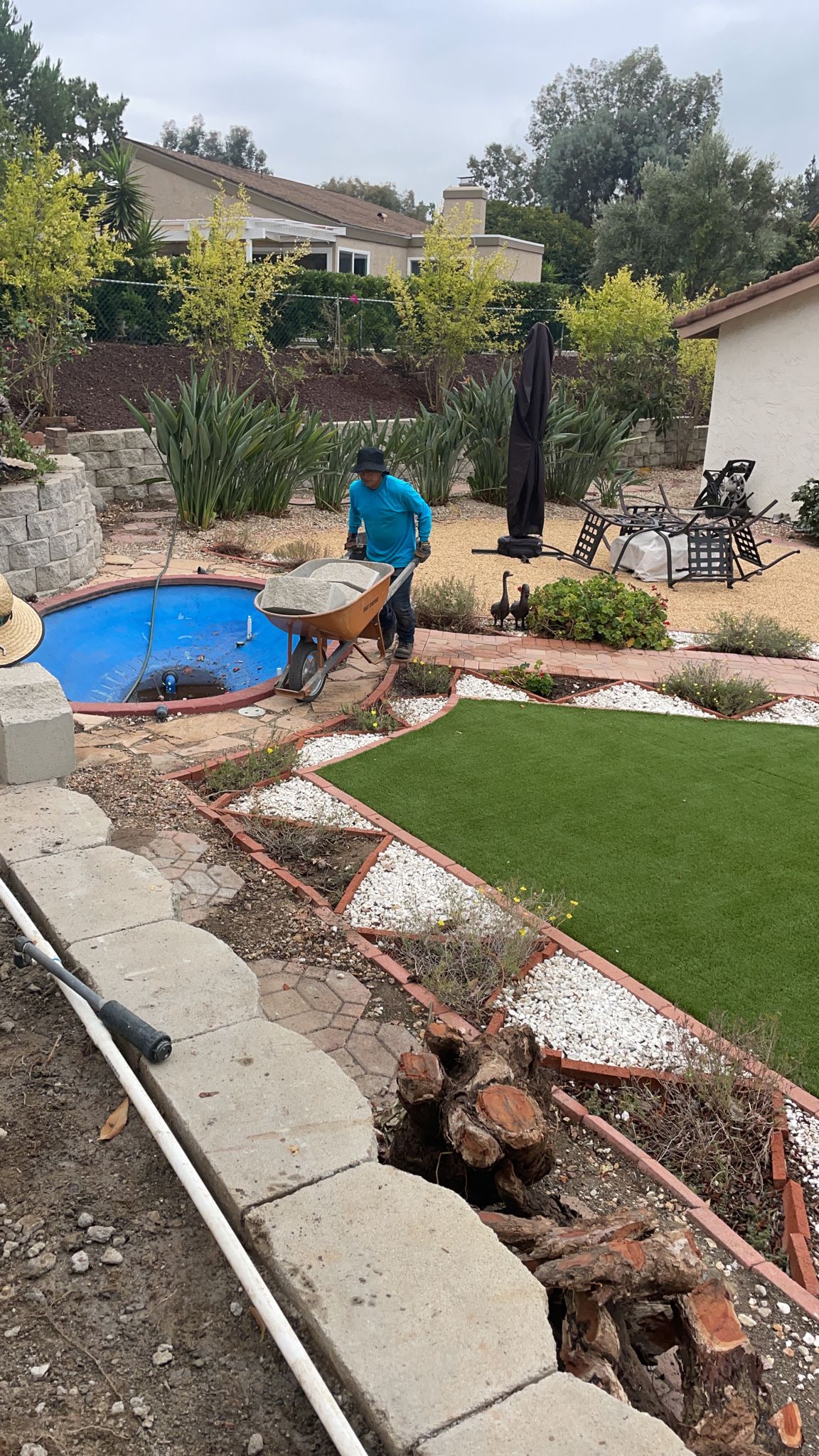 Landscaping crew working on backyard with turf and pond features